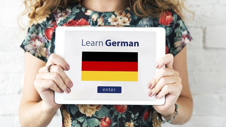 Women holding a tablet, which shows the words leran german and the german flag