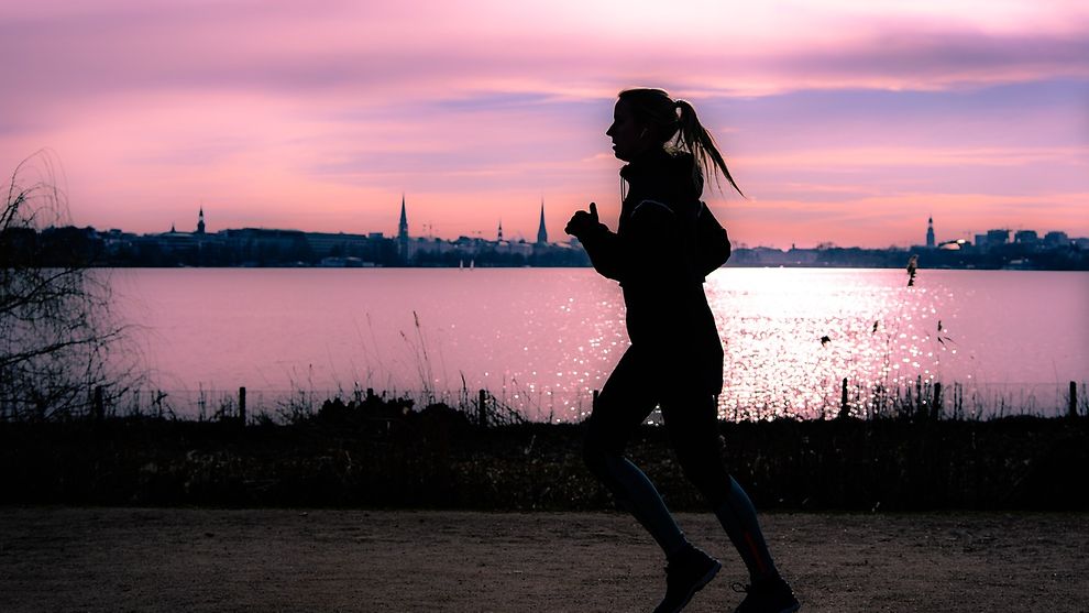  Woman jogging along the banks of the Alster lake