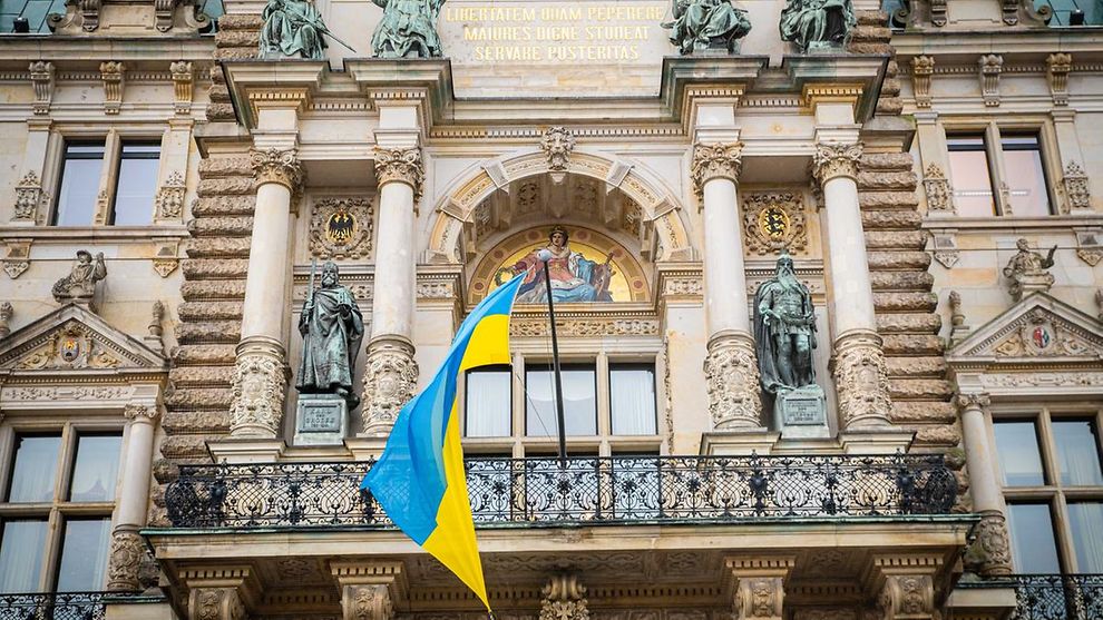The Ukrainian national flag in blue and yellow flying from the Hamburg Rathaus city hall