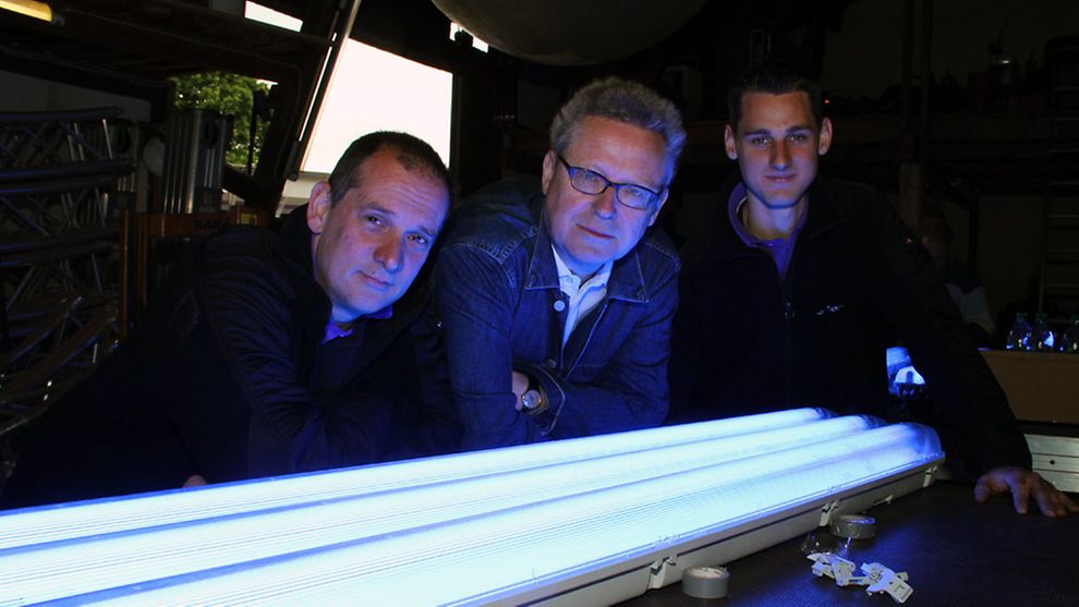 Michael Batz (centre) with team members in front of fluorescent tubes