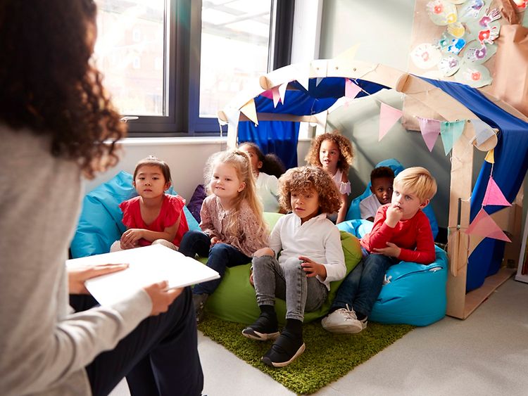  A kindergarten teacher reading a book to a group of children