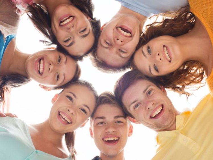  Seven young persons arranged in a circle smiling into the camera