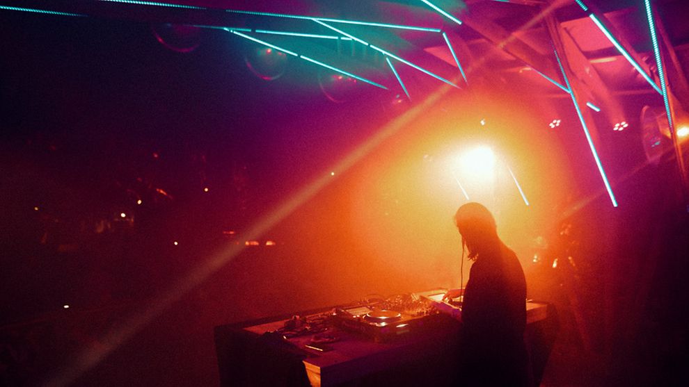 A DJ spins on stage amidst colourful lights