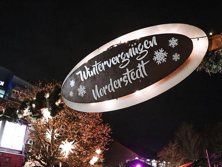  A sign spelling out 'Wintervergnügen Norderstedt' against a festive background